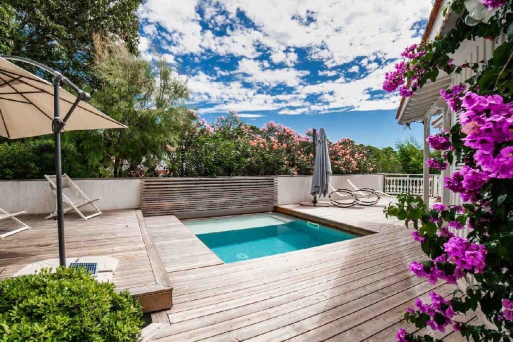 Terrasse en bois avec piscine intégrée et végétation luxuriante, conçue par un architecte paysagiste pour un aménagement extérieur harmonieux et fonctionnel.